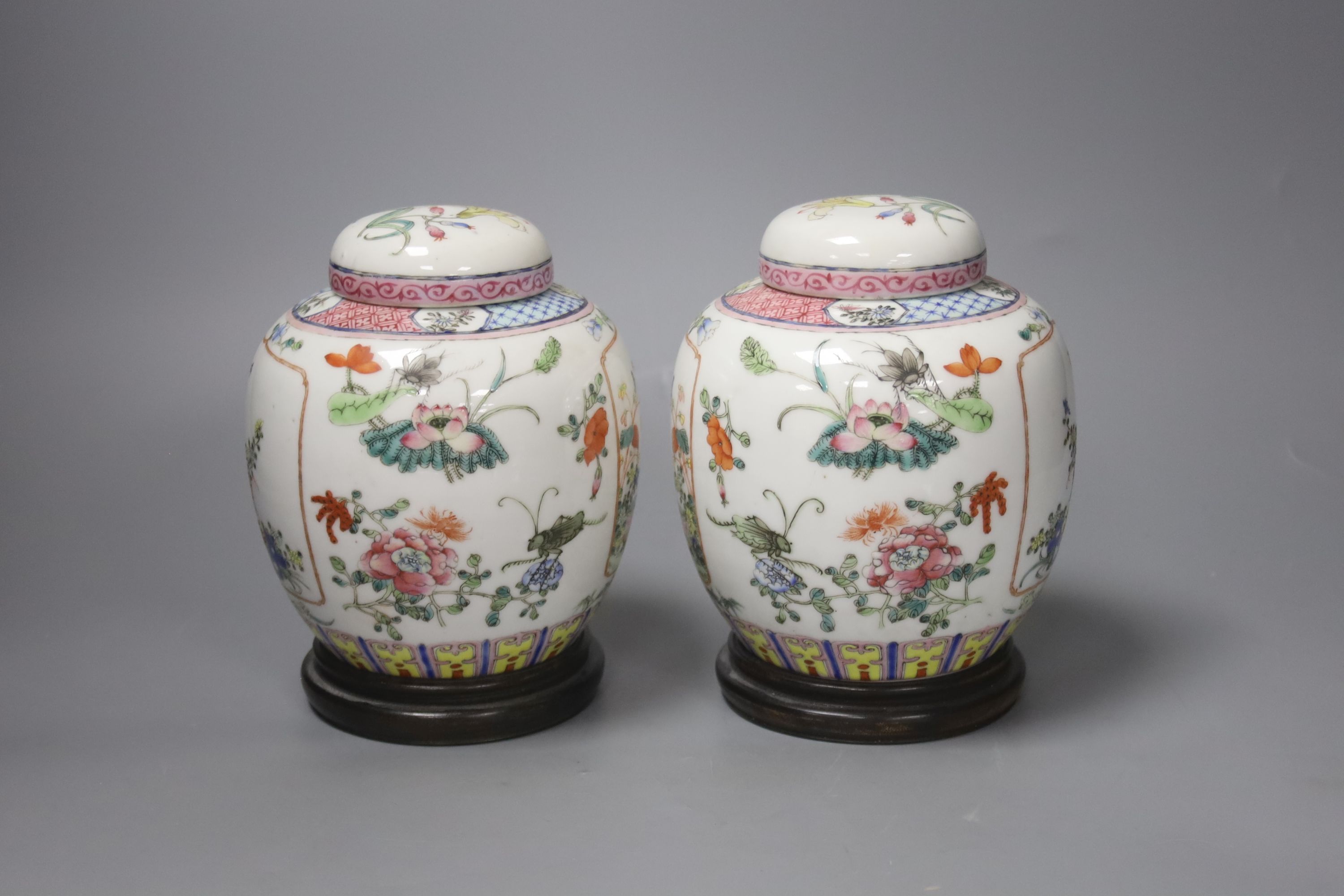 A pair of Chinese famille rose jars and covers, late 19/early 20th century, 15.5cm, on hardwood stands